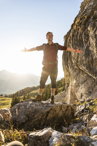 Wanderer, der in den Bergen steht und jubelt, lizenzfreies Stockfoto