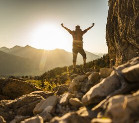 Hiking man standing in he mountains, cheering - UUF16015