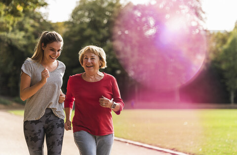 Enkelin und Großmutter haben Spaß, joggen zusammen im Park, lizenzfreies Stockfoto