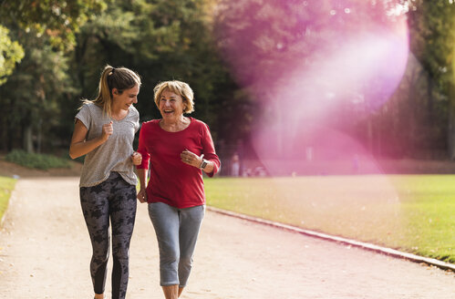 Granddaughter and grandmother having fun, jogging together in the park - UUF16056