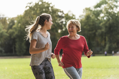 Granddaughter and grandmother having fun, jogging together in the park - UUF16061