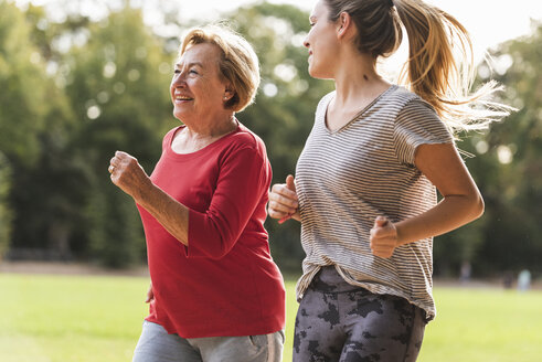 Granddaughter and grandmother having fun, jogging together in the park - UUF16062