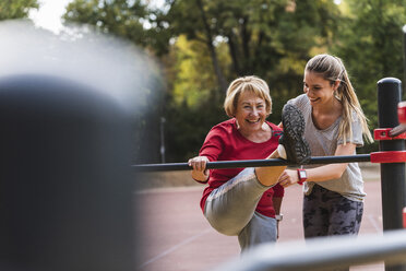 Grandmother and granddaughter training on bars in a park - UUF16066