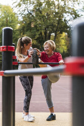 Grandmother and granddaughter training on bars in a park - UUF16067