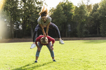 Granddaughter leapfrogging over her grandmother in a park - UUF16070