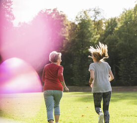 Granddaughter and grandmother having fun, jogging together in the park - UUF16077