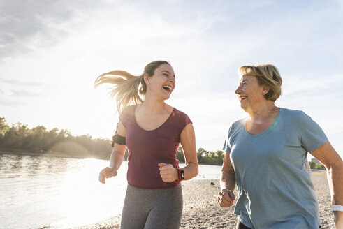 Enkelin und Großmutter haben Spaß, joggen zusammen am Fluss - UUF16080