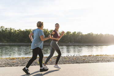 Granddaughter and grandmother having fun, jogging together at the river - UUF16082