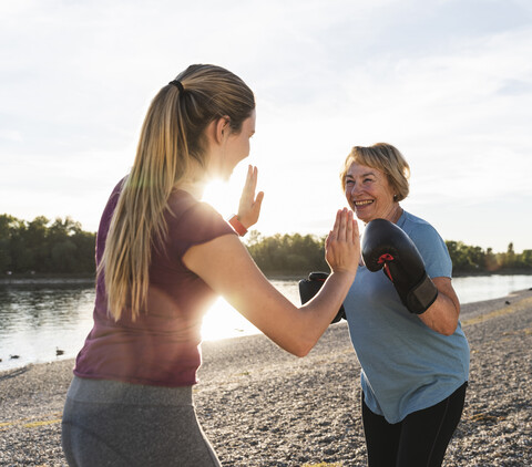 Großmutter beim Boxtraining mit ihrer kleinen Tochter am Fluss, lizenzfreies Stockfoto