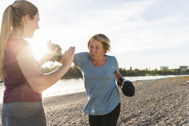 Großmutter beim Boxtraining mit ihrer kleinen Tochter am Fluss - UUF16099