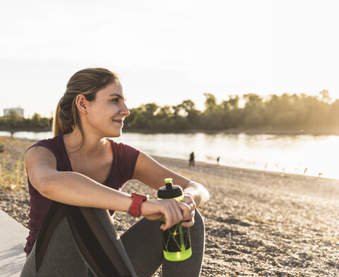 Junge Frau, die nach dem Sport am Fluss eine Pause einlegt, lizenzfreies Stockfoto