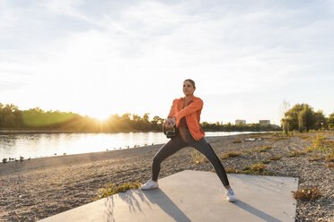 Young woman exercising with a kettlebell at the river - UUF16120