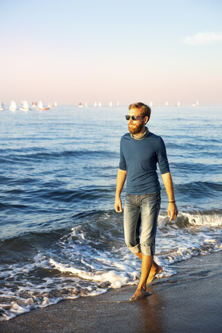 Junger Mann beim abendlichen Spaziergang am Strand, lizenzfreies Stockfoto