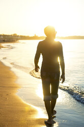 Silhouette of man walking at the beach at sunset - PUF01345