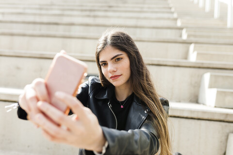 Junge Frau auf einer Treppe, die ein Selfie macht, lizenzfreies Stockfoto