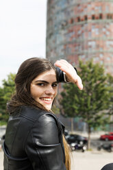 Spain Barcelona, portrait of smiling young woman in the city shielding eyes - VABF01954