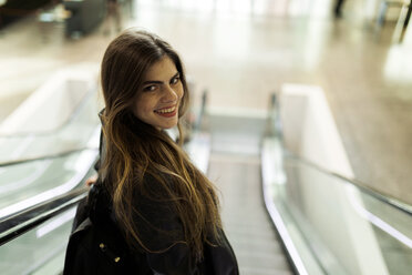 Porträt einer lächelnden jungen Frau auf einer Rolltreppe - VABF01973