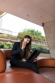 Glückliche junge Geschäftsfrau sitzt in einer Lounge und benutzt ein Tablet für eine Videokonferenz - VABF01997