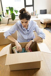 Junge Frau beim Auspacken eines Kartons in einer neuen Wohnung - VABF02011