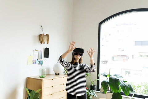 Young woman at home wearing VR glasses stock photo