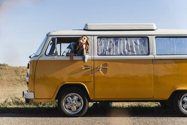 Pretty woman on a road trip with her camper, looking out of car window - UUF16130