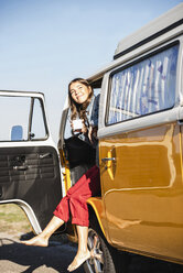 Pretty woman on a road trip with her camper, taking a break, drinking coffee - UUF16144