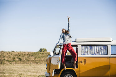 Pretty woman on a road trip with her camper, cheering, enjoying freedom - UUF16151