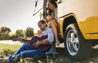 Zärtliches Paar auf einer Autoreise, macht eine Pause, spielt Gitarre - UUF16168