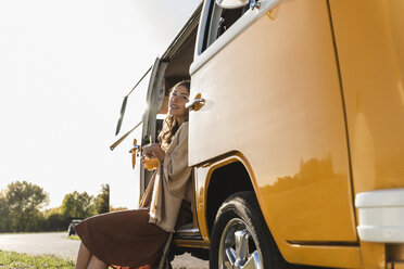 Hübsche Frau auf einem Roadtrip mit ihrem Wohnmobil, macht eine Pause, trinkt Saft - UUF16171