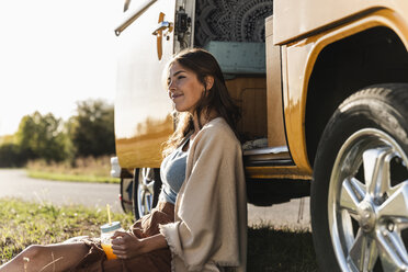 Pretty woman on a road trip with her camper, taking a break, drinking juice - UUF16173