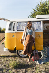 Hübsche Frau auf einem Roadtrip mit ihrem Wohnmobil, trinkt Bier, hält Gitarre - UUF16183