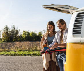 Couple on a road trip fixing surfboard at their camper - UUF16187