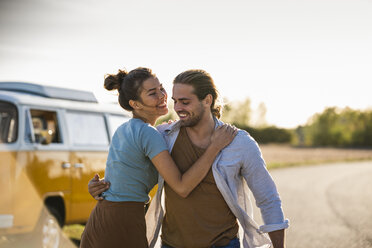 Happy couple doing a road trip with a camper, embracing on the road - UUF16196