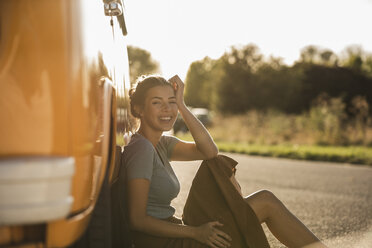 Pretty woman on a road trip with her camper, relaxing at the roadside - UUF16213