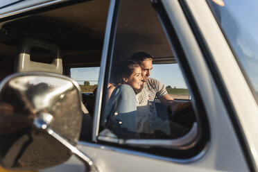 Verliebtes Paar, das in seinem Wohnmobil sitzt und den Sonnenuntergang beobachtet - UUF16221