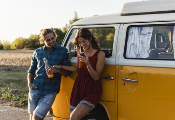 Happy couple taking a break on their road trip, having a drink - UUF16240