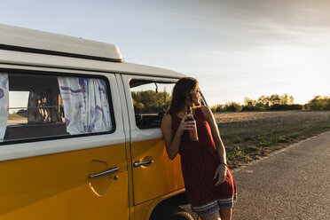 Hübsche Frau auf einer Autoreise mit ihrem Wohnmobil, die bei Sonnenuntergang eine Pause einlegt - UUF16241