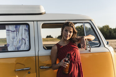 Pretty woman on a road trip with her camper, taking a break at sunset - UUF16242