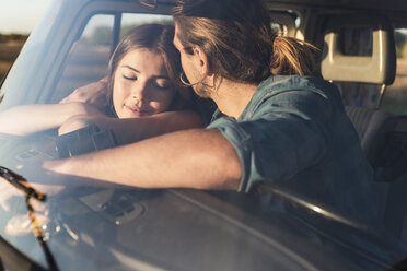 Romantic couple sitting in their camper with arms around - UUF16251