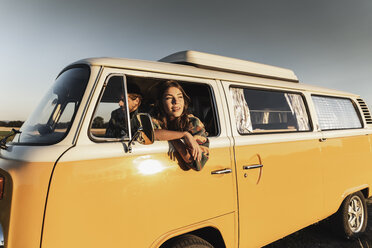 Happy couple sitting in their camper, watching the sunset - UUF16262