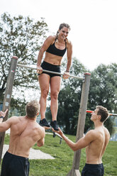 Sportive team during workout, men helping woman on bar, outdoor - HMEF00130