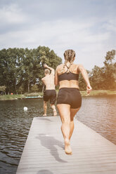 Sportliche Menschen laufen auf dem Steg und springen nach dem Training in den See - HMEF00162