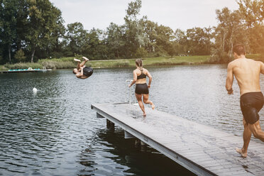 Sportliche Menschen laufen auf dem Steg und springen nach dem Training in den See - HMEF00163