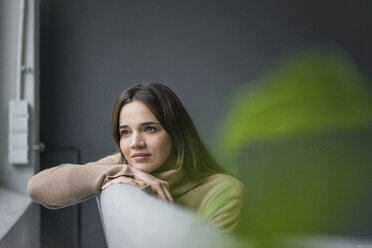 Porträt einer träumenden Frau auf der Couch mit Blick aus dem Fenster - MOEF01834