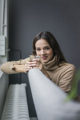 Portrait of smiling woman relaxing on couch with glass of coffee - MOEF01835