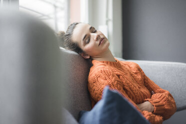 Portrait of woman wearing orange knit pullover having a break on the couch - MOEF01848