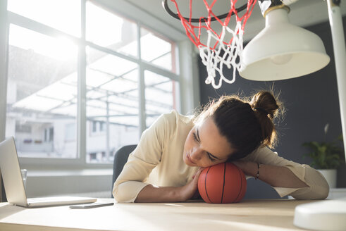 Freelancer entspannt mit Basketball am Schreibtisch in einem Loft - MOEF01858