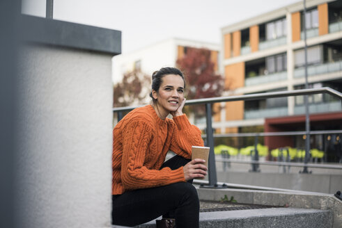 Porträt einer eleganten Frau mit Kaffee zum Mitnehmen, die auf einer Treppe im Freien sitzt - MOEF01877