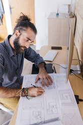 Young architect working at home with blueprints - JRFF02166