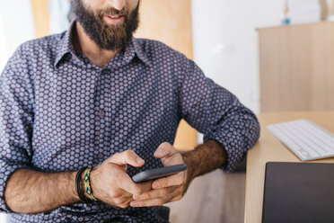 Close-up of young man using cell phone at home - JRFF02176